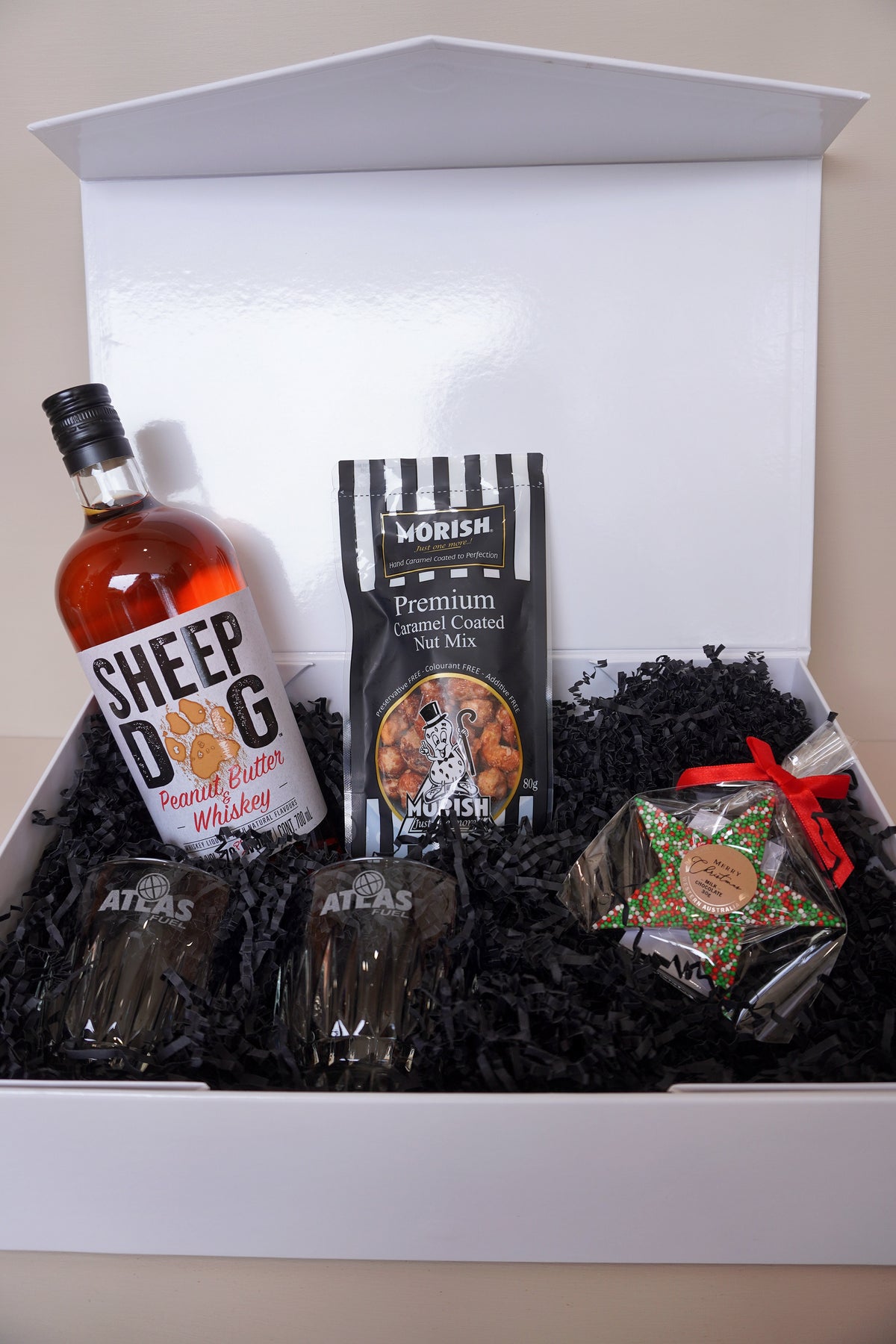 Open bespoke corporate gift box for Atlas Fuel containing Sheep Dog whiskey, Morish caramel nut mix, Atlas-branded glasses and a festive star treat, by No Matter What Gift Box Perth