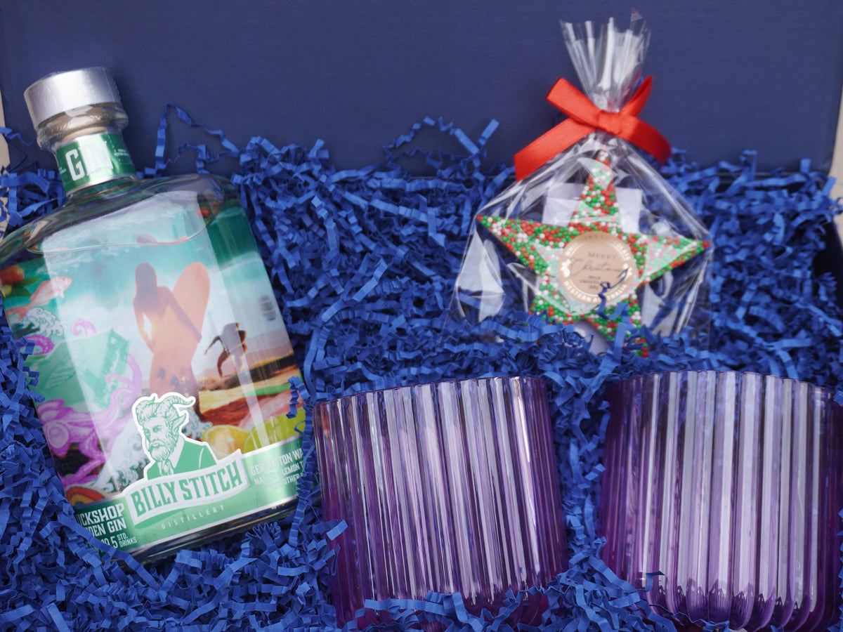 Gift box holding a bottle of Billy Stitch Tuckshop Gin with two ribbed tumblers and a decorated star biscuit on blue shred, a Perth distiller featured in No Matter What Gift Box corporate gift boxes